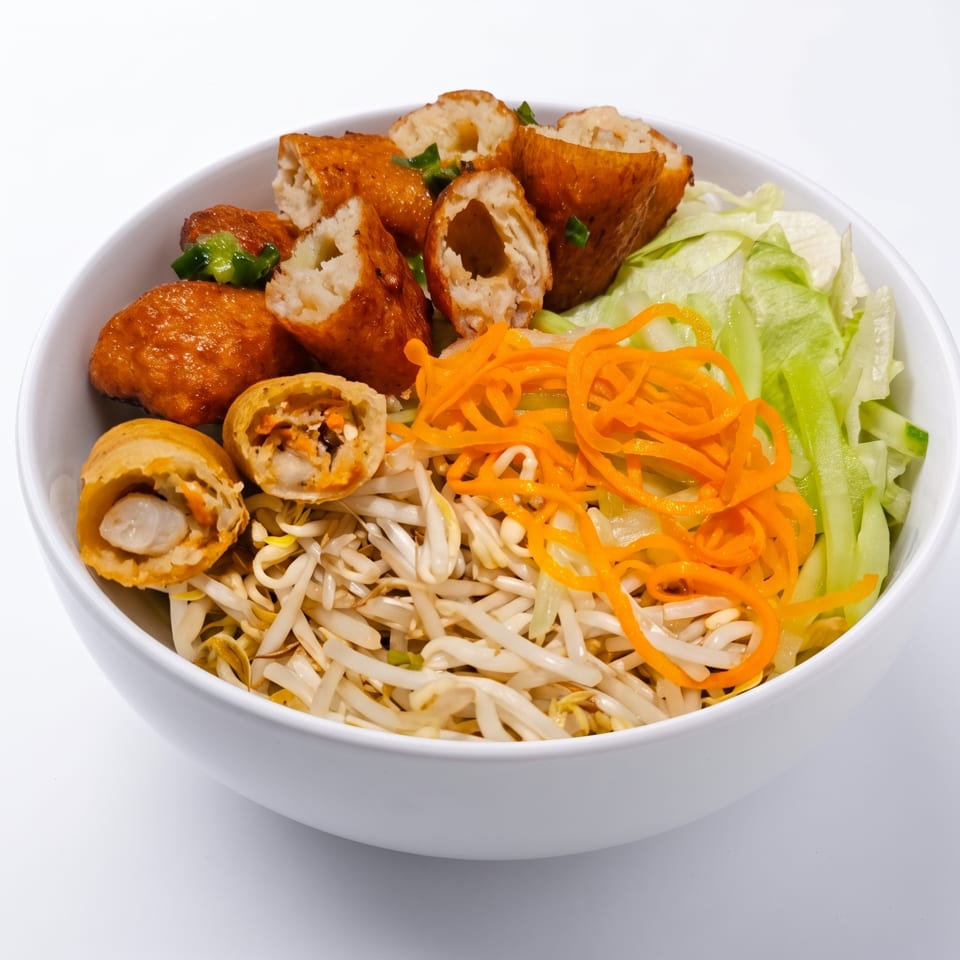 A white bowl filled with fried spring rolls, bean sprouts, shredded carrots, and lettuce.